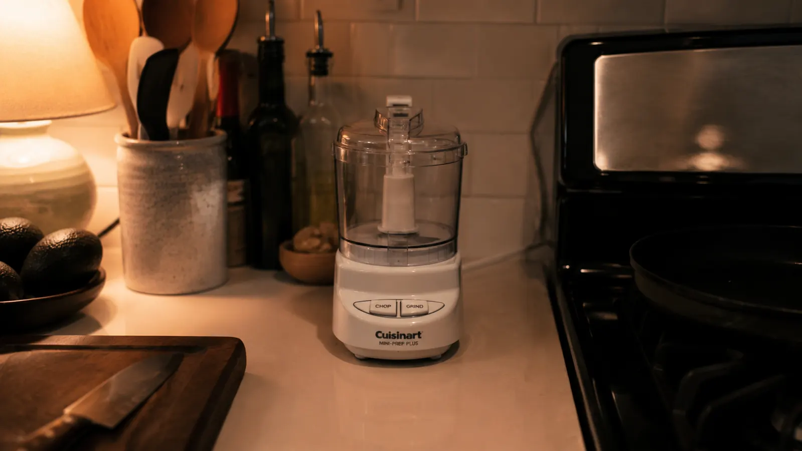 Cuisinart Mini-Prep Plus food processor sitting on a compact kitchen counter beside the stove at night