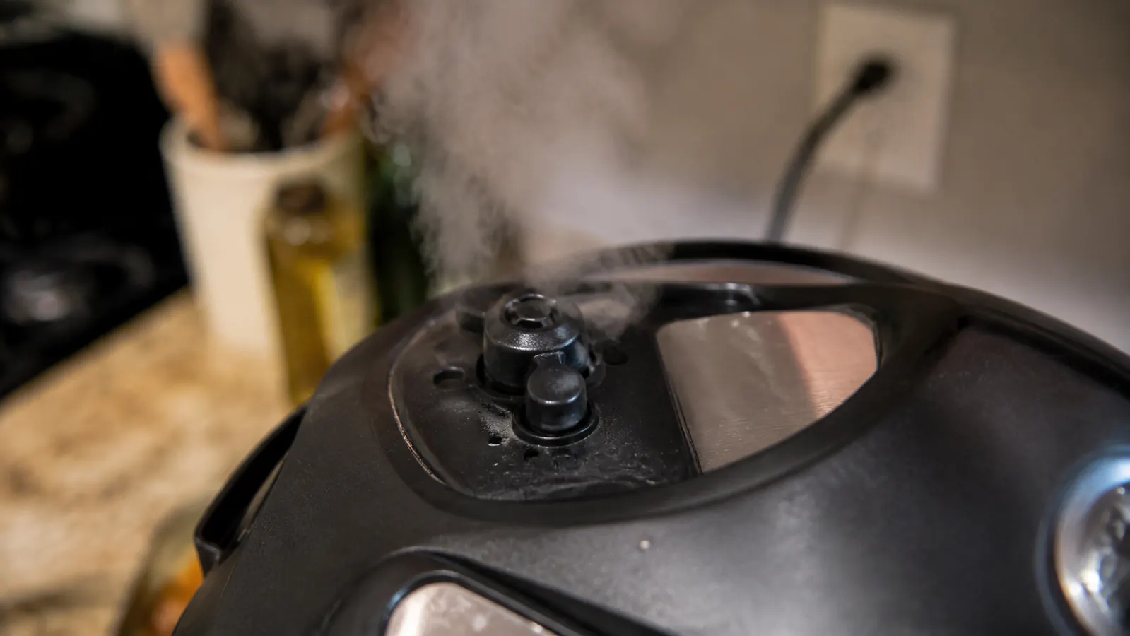 Steam rising visibly from the vent hole on the Dash Mini Rice Cooker's lid during a cook cycle